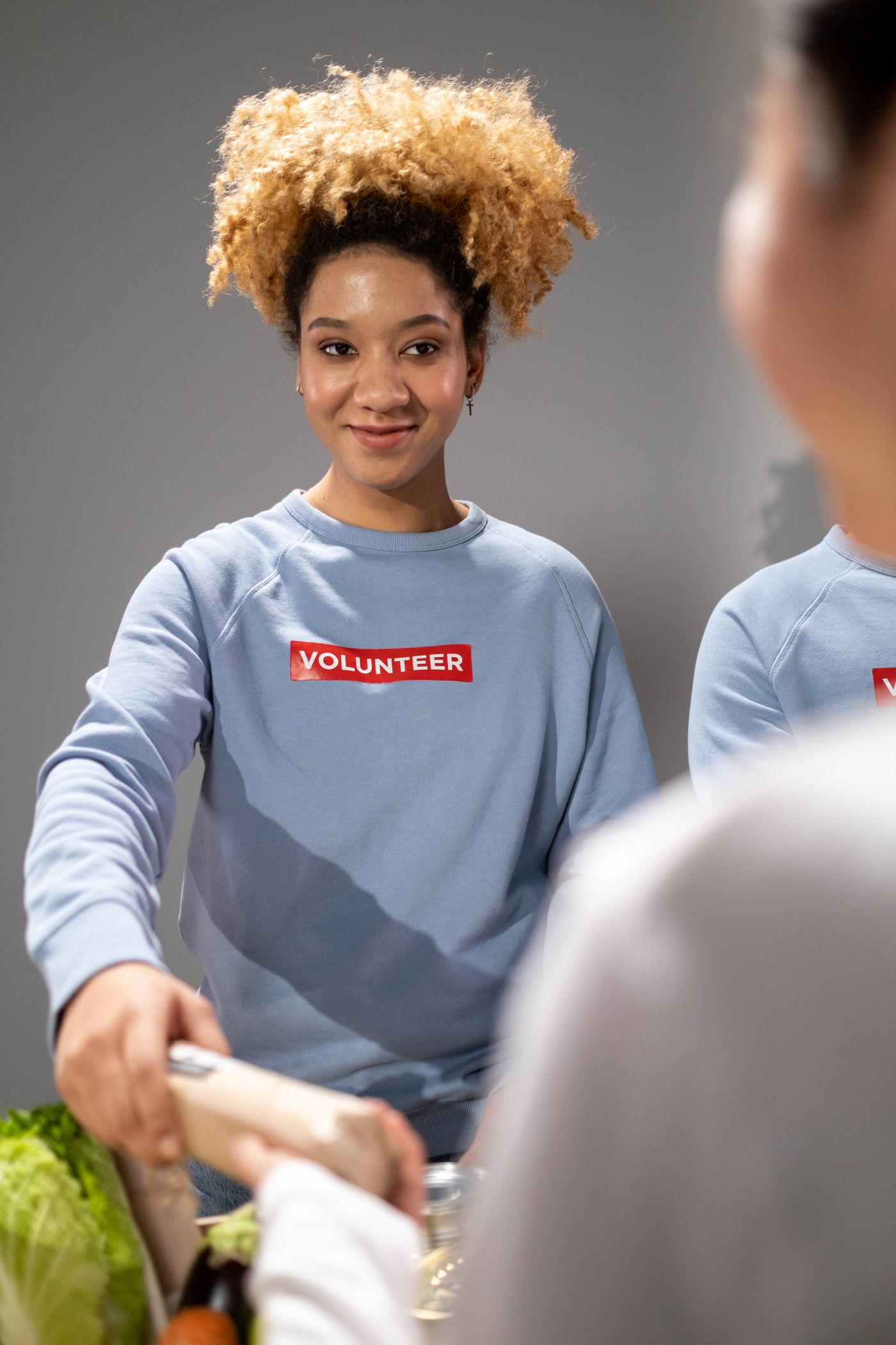 A volunteer handing groceries to someone.